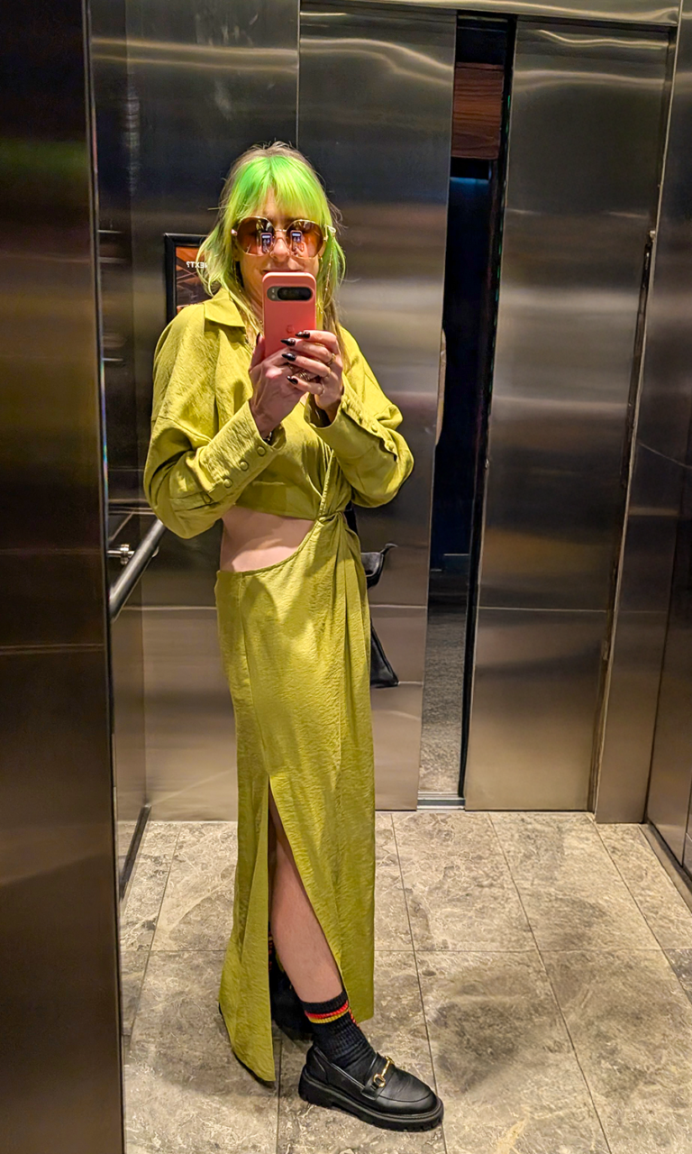 Ange has green hair and is wearing a green dress, she's taken the photo of her reflection in an elevator with her phone
