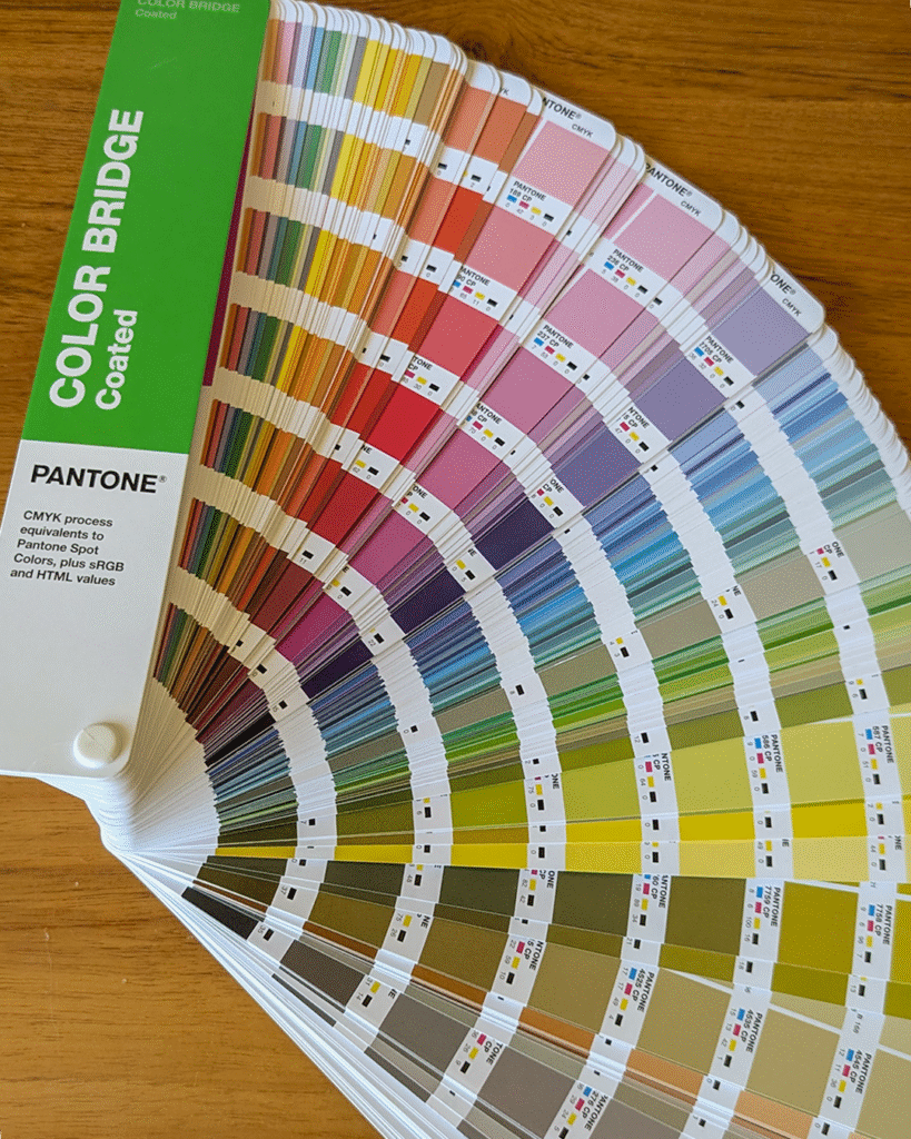 Pantone Color Bridge book fanned out to reveal the rainbow of colours referenced in the guide swatches
